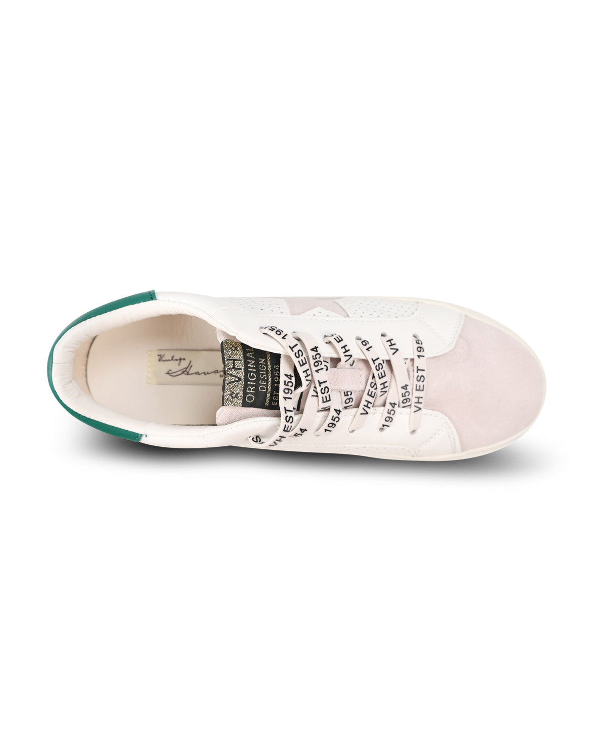 A single low-top sneaker shown from a top-down view on a white background. The shoe features a white leather upper with a nude suede toe cap, black text printed on the laces, and a green heel accent.