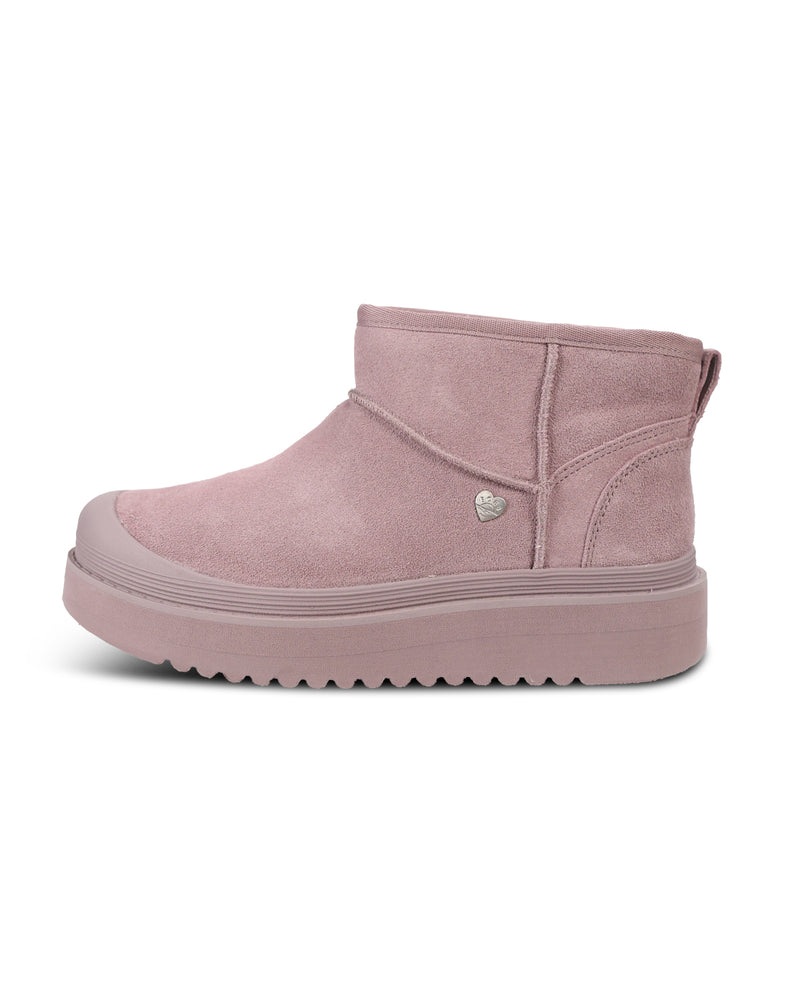 A dusty pink suede ankle boot with a chunky platform sole and a small silver heart-shaped metal emblem on the side, shown against a plain white background.