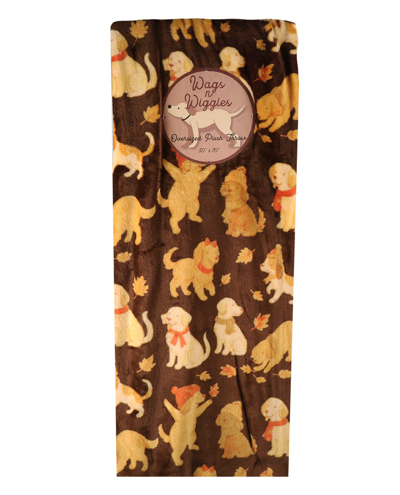 A rectangular plush blanket featuring a repeating pattern of cartoon dogs in cream, yellow, and orange on a dark brown background. A circular fabric label is sewn into the top center, reading 'Wags of Wiggles Orange Pet Blanket'.