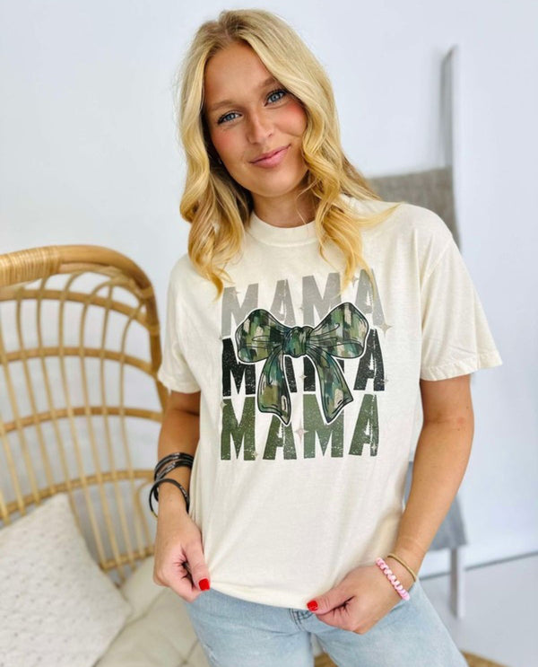 Woman wearing a white t-shirt with 'MAMA' text and camouflage bow graphic.