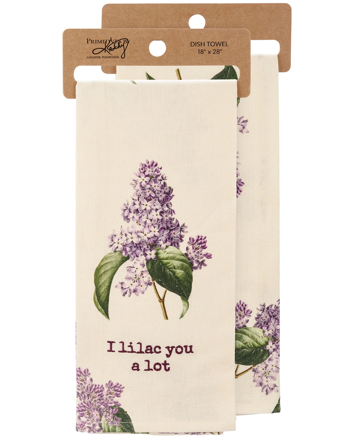A cream-colored dish towel with a purple lilac floral print and the text 'I'll lac you a lot' in purple, hanging from a brown kraft paper hanger. A second identical towel is partially visible behind it.