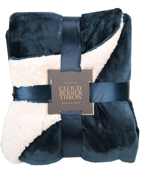 A folded plush throw blanket with a navy blue velvety exterior and cream sherpa lining, wrapped in a dark satin ribbon with a central label reading 'Cloud Berber Throw'.