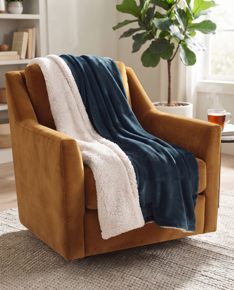 A mustard yellow velvet armchair in a bright living room, draped with a cream sherpa throw and a navy blue blanket.