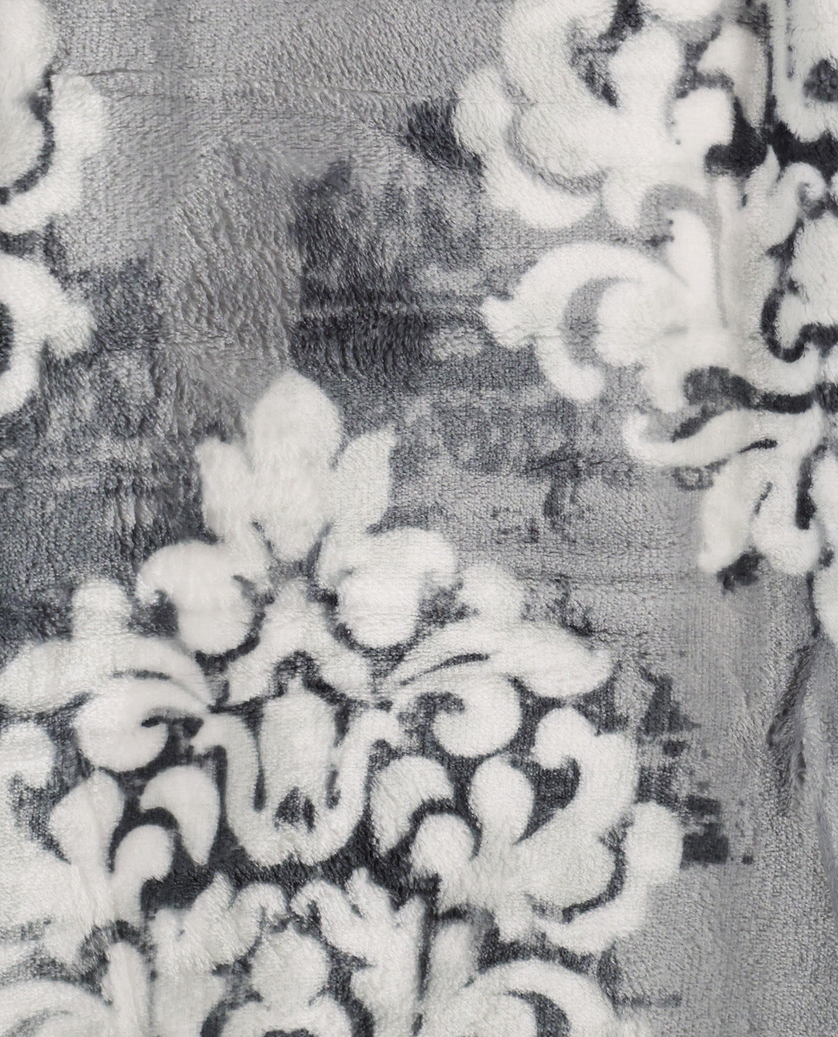 A close-up of a plush fabric with a distressed damask pattern in gray, white, and black.