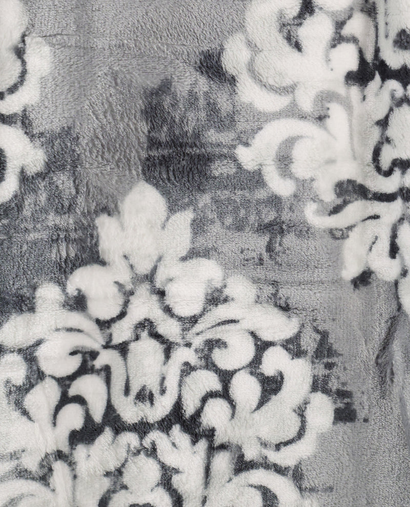 A close-up of a plush fabric with a distressed damask pattern in gray, white, and black.
