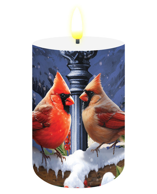 Candle with a design of two cardinals in a snowy landscape