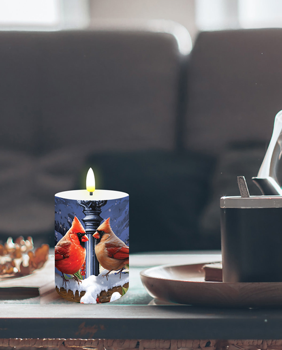 Candle with a design of cardinals on a table in a living room setting