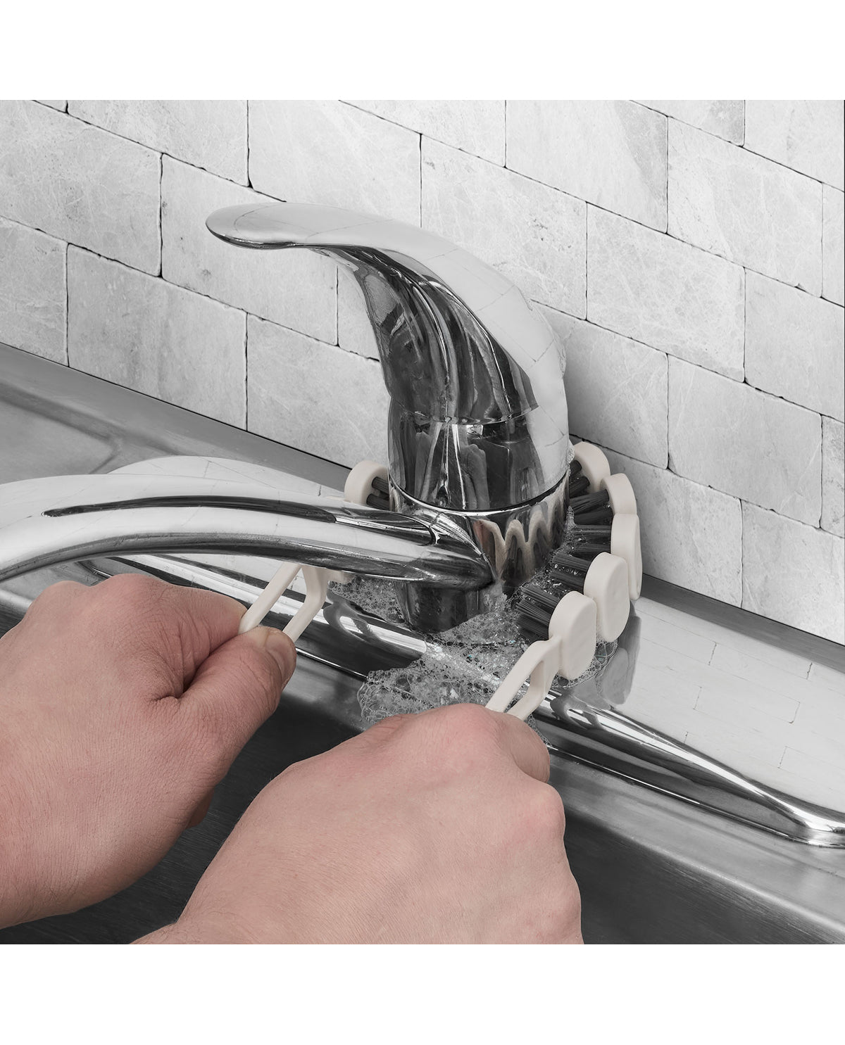 A close-up of a chrome kitchen faucet installed in a sink, with a white plastic clip holding the faucet in place against a light gray tiled backsplash. Two hands are visible adjusting the white clip.