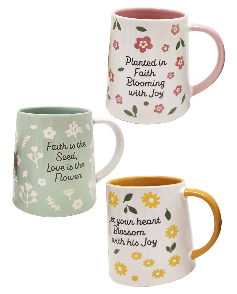 Three ceramic mugs with floral patterns and inspirational quotes on a plain white background. One mug is light green with white flowers and the quote 'Faith is the seed, Love is the flower.