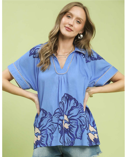 Woman wearing a blue floral blouse against a light green background