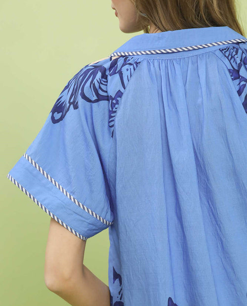 Light blue blouse with purple patterns on a green background