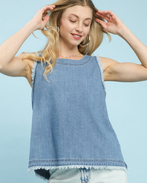 A woman wearing a light blue denim sleeveless top with raw, frayed edges, posed against a solid light blue background.