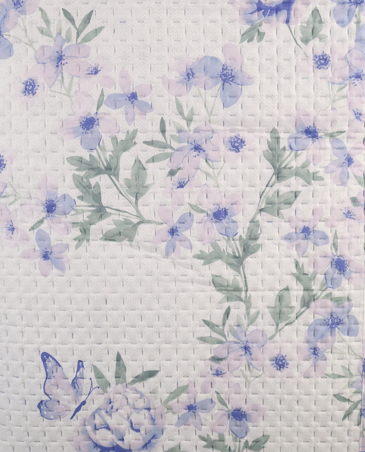 A close-up of a quilted fabric featuring a delicate floral pattern with light purple and blue flowers, green leaves, and a small blue butterfly on a white textured background.