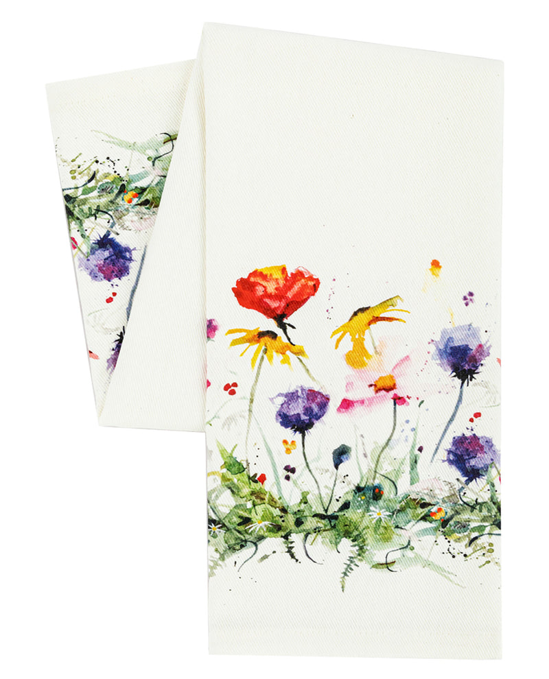 A white kitchen towel featuring a colorful watercolor floral print of red, yellow, purple, and pink wildflowers with green stems, shown with a second towel folded behind it on a white background.