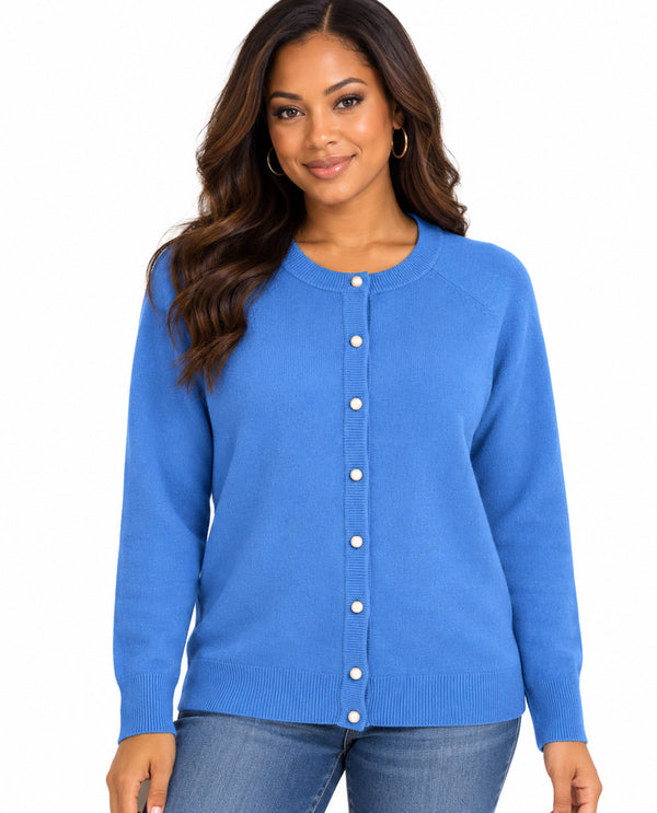 A woman wearing a blue long-sleeve button-up cardigan sweater and blue jeans, standing against a plain white background.