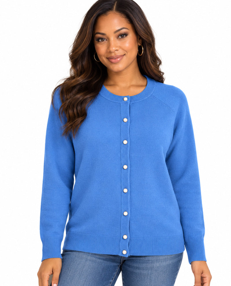 A woman wearing a blue long-sleeve button-up cardigan sweater and blue jeans, standing against a plain white background.