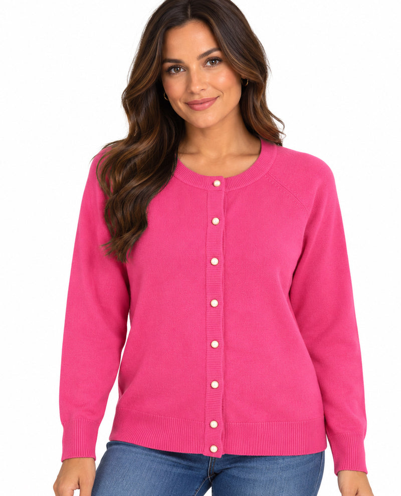 A woman wearing a pink long-sleeve button-up cardigan sweater and blue jeans, standing against a plain white background.