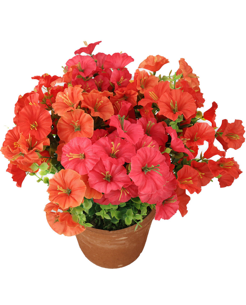 A potted artificial flower arrangement featuring vibrant red, orange, and pink petunia-like blooms with green leaves in a brown pot, isolated on a white background.