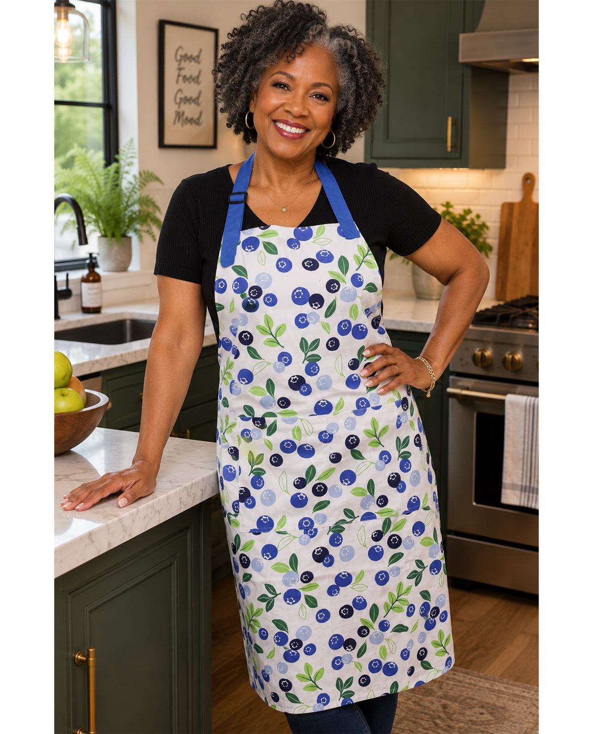 Woman wearing a blueberry patterned apron in a kitchen.