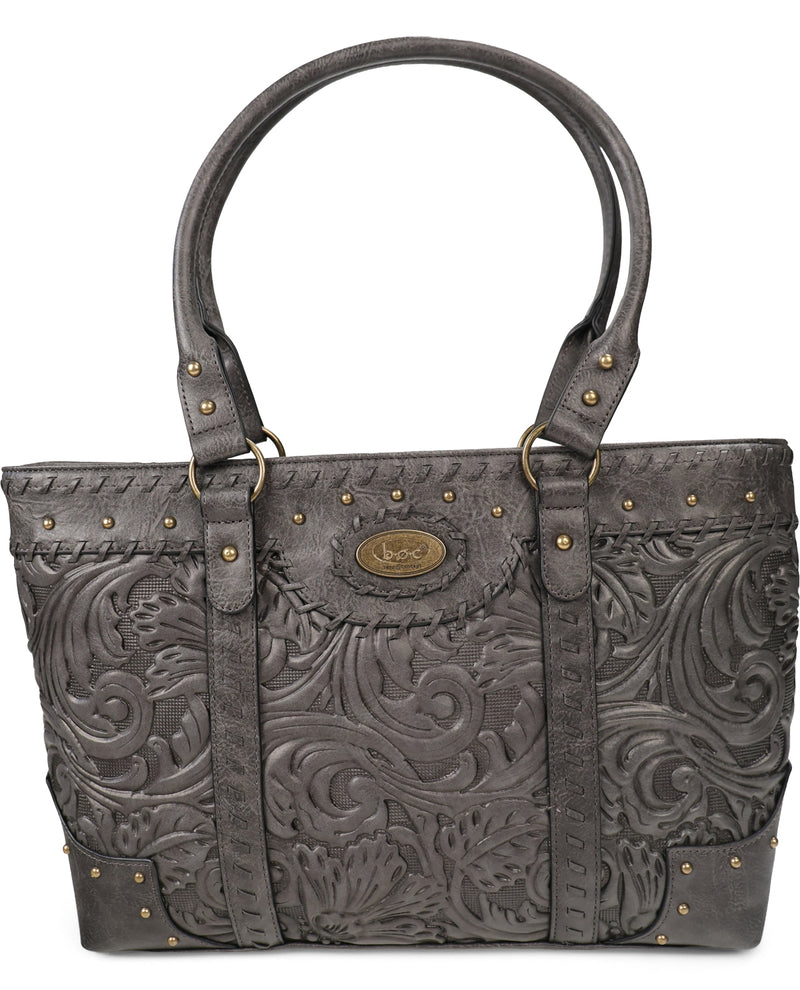 A dark gray tooled leather handbag with embossed floral scrollwork, brass-tone studs, and double top handles, shown against a plain white background.