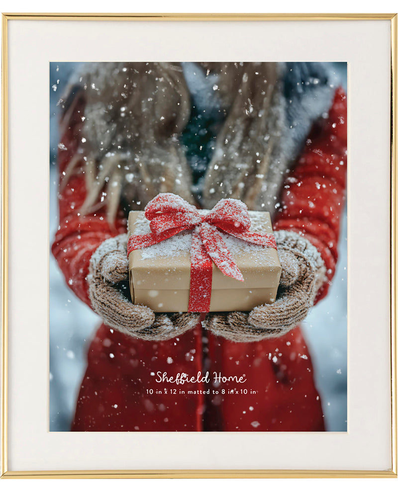 Framed print of hands holding a gift with a red ribbon against a snowy background, featuring 'Sheffield Home' branding.