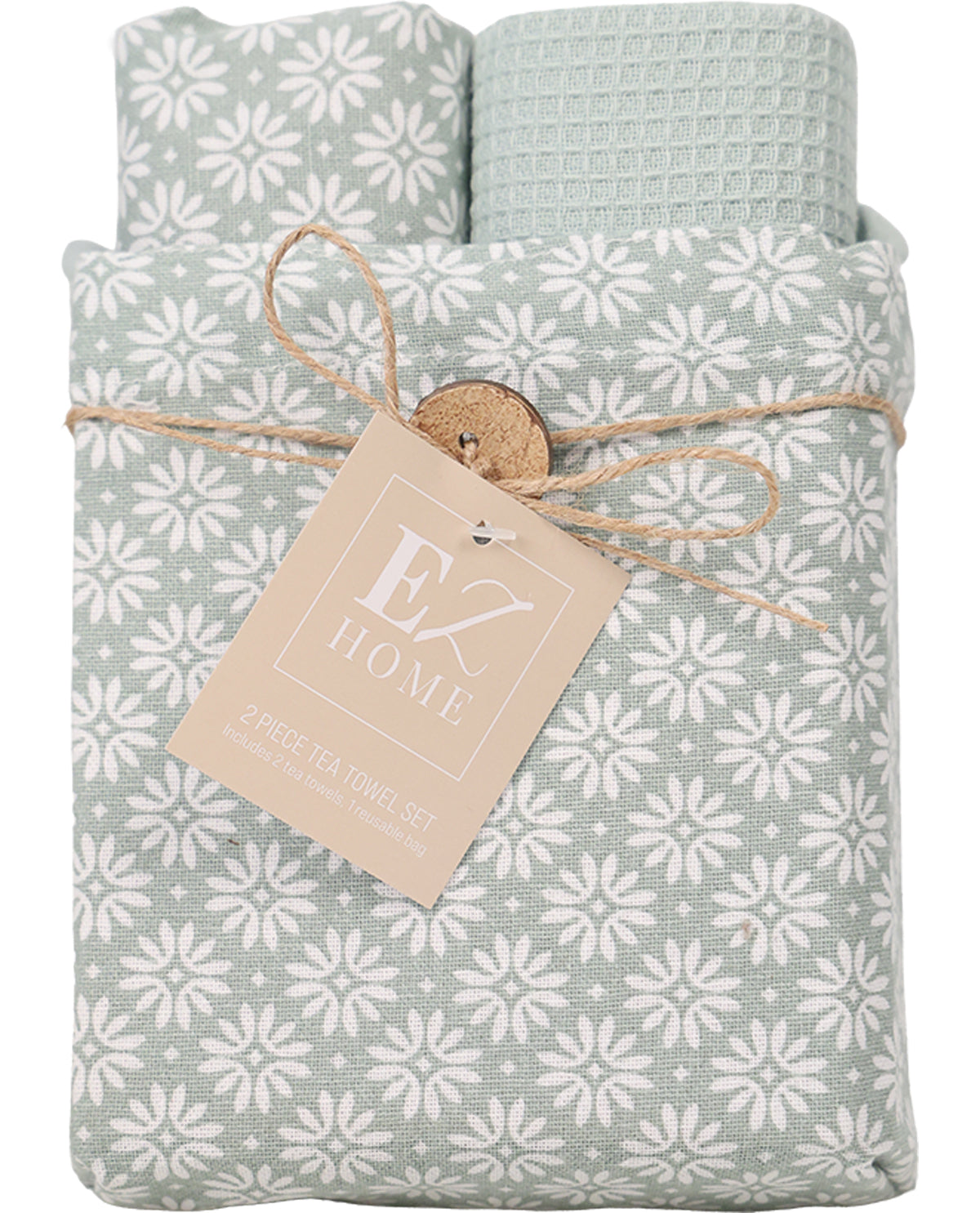 A folded tea towel set wrapped in twine with a paper tag reading 'EX HOME 2 PIECE TEA TOWEL SET.' The towels have a pale sage green and white floral snowflake pattern, with one towel showing a textured waffle weave.