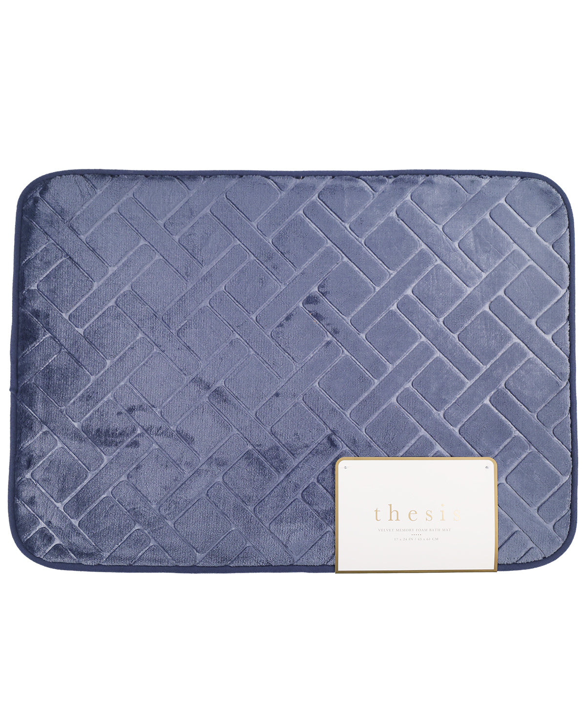 A navy blue quilted bath mat with a geometric diamond pattern, featuring a small white brand tag that reads 'thesa' in the bottom right corner.