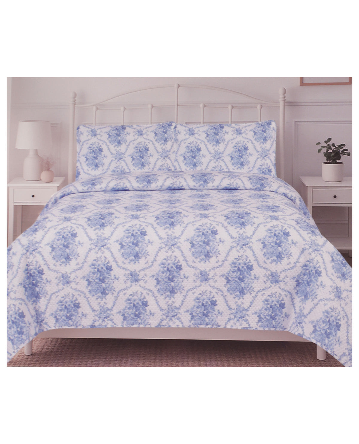 A bed dressed in a white and blue damask-patterned bedding set, including a comforter and two matching pillowcases, shown in a bedroom setting with white nightstands and lamps.