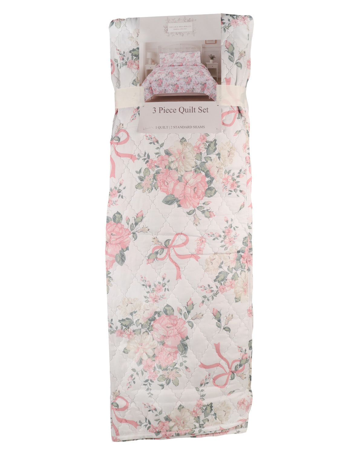 A packaged 3-piece quilt set featuring a vintage-style floral print with pink roses, green leaves, and pink ribbon motifs on a light cream background. The set is wrapped in a protective paper sleeve with a small inset showing the matching pillowcase.