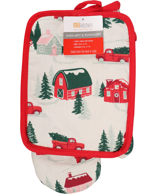 A matching oven mitt and pot holder set with a red border and a winter farm print featuring red trucks, barns, and evergreen trees. The oven mitt has a paper tag attached that reads 'mukitchen' and 'Oven Mitt & Pot Holder'.