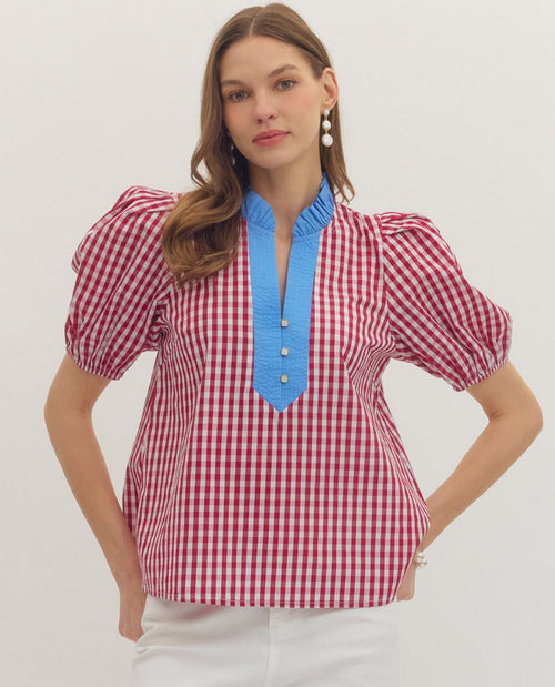 Woman wearing a red and white checkered blouse with blue neckline on a white background