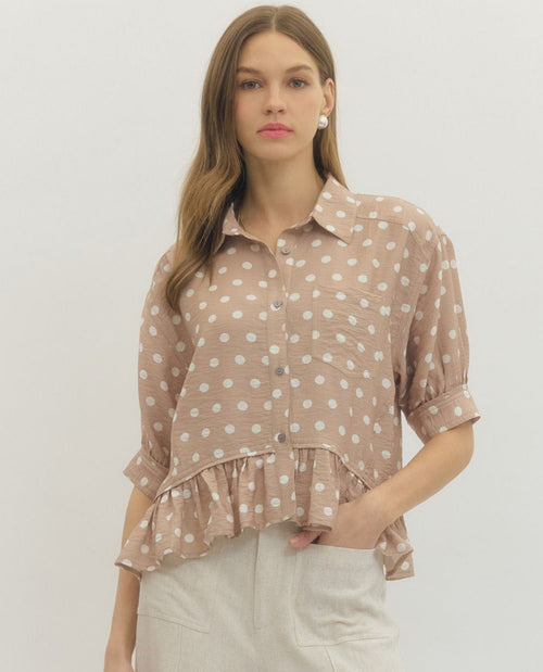 Woman wearing a polka dot blouse with a plain background
