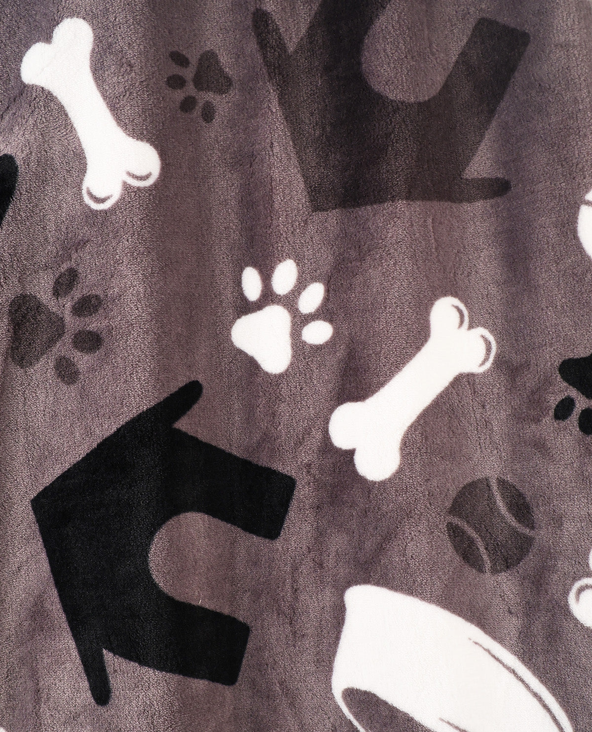 A close-up of a plush fabric with a dog-themed pattern featuring black and white bones, paw prints, and arrows on a dark gray background.