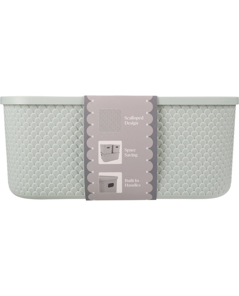 A light gray scalloped bath basket with a textured honeycomb pattern and a central gray paper label, shown against a plain white background.