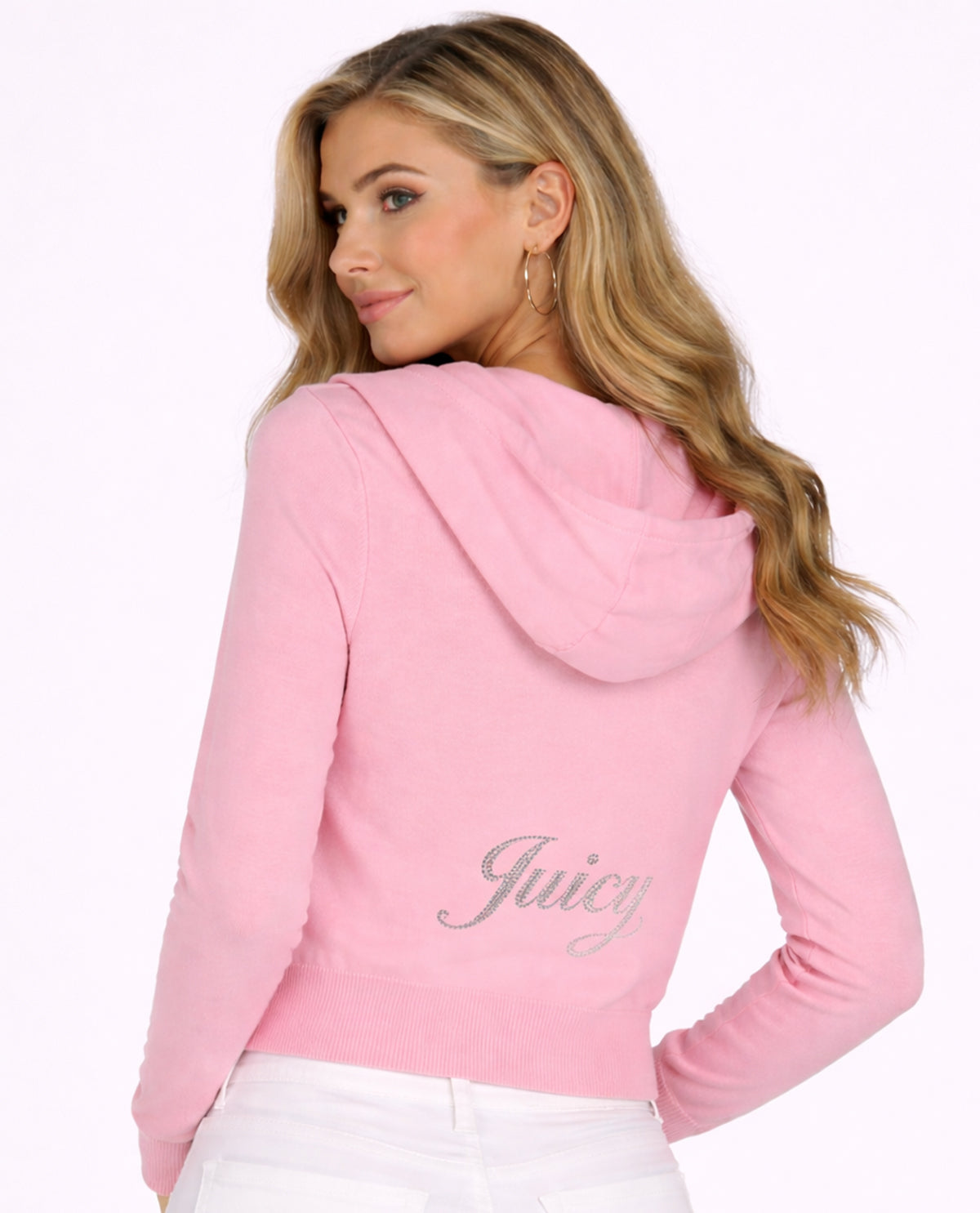 A woman wearing a pink hooded sweatshirt with a silver 'Juicy' script logo on the back, shown from a rear three-quarter view against a plain white background.