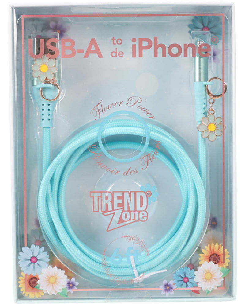 A light blue braided USB-A to iPhone charging cable in its original retail packaging. The cable features decorative daisy flower charms on both ends and is coiled inside a clear plastic box with floral graphics and the brand name 'TREND Zone' visible.