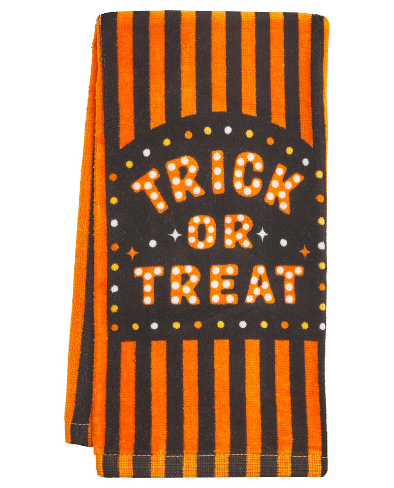 A folded Halloween-themed kitchen towel or tea towel featuring orange and black vertical stripes with a central black arch containing the words 'TRICK OR TREAT' in orange letters outlined with white dots.