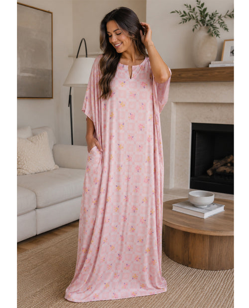 Woman wearing a pink floral caftan night gown in a living room setting