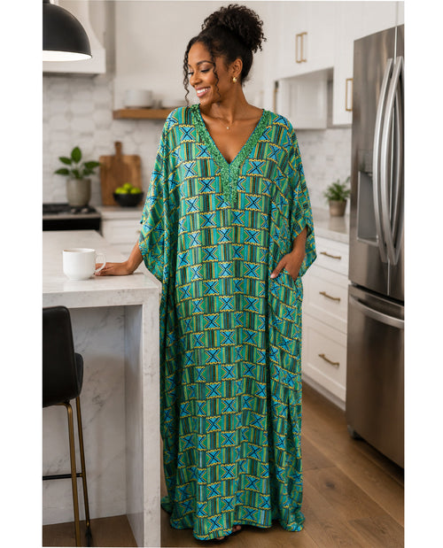 Woman in a green patterned dress standing in a kitchen.