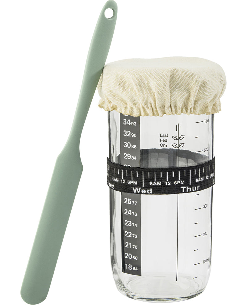 Clear measuring container with a green spoon and white lid on a white background