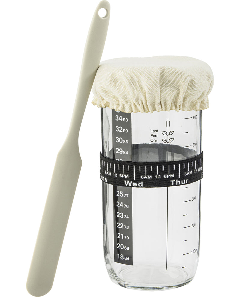 Glass measuring container with a lid and spoon on a white background