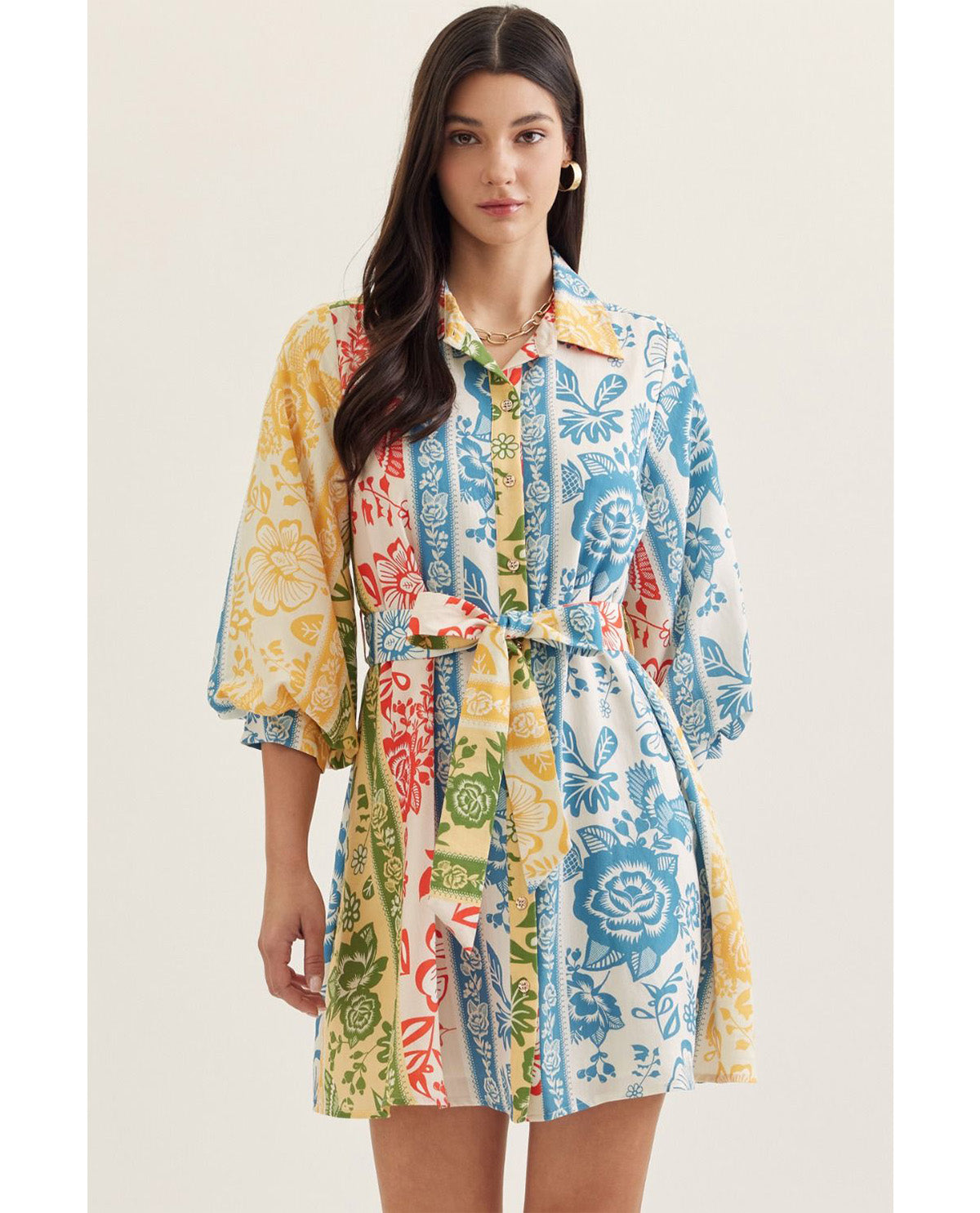 Woman wearing a colorful patterned dress on a plain background