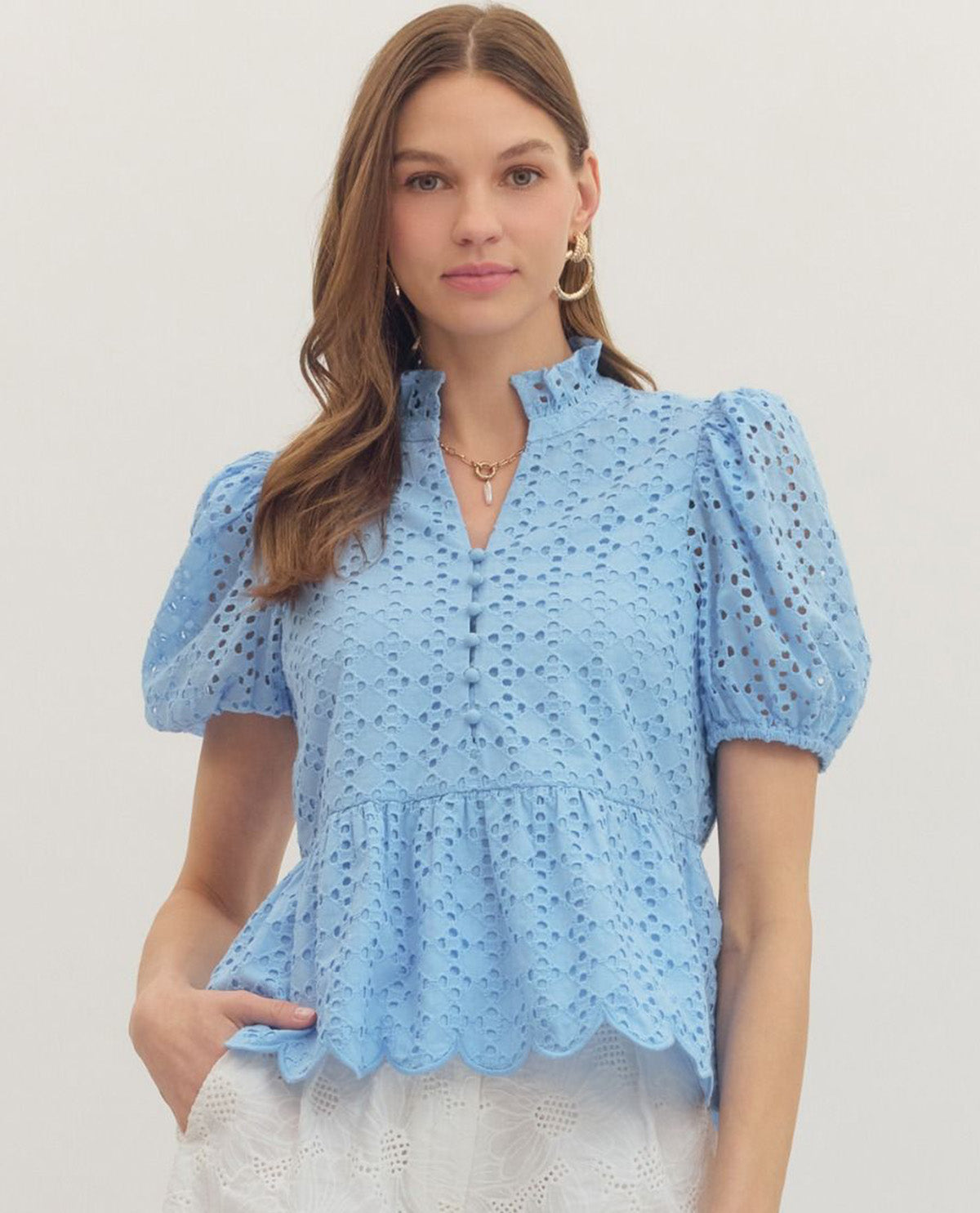 Woman wearing a light blue blouse with puff sleeves on a plain background
