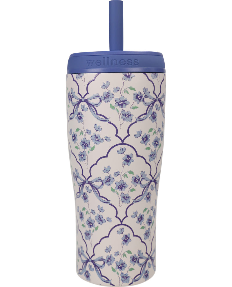 A tall insulated tumbler with a blue lid and straw, featuring a white body decorated with a blue and green floral trellis pattern. The brand name 'wellness' is embossed on the blue lid.