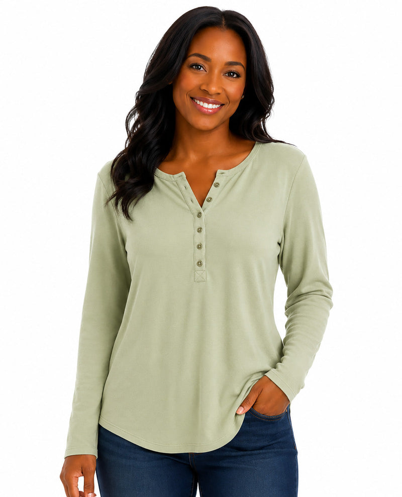A woman wearing a sage green long-sleeve henley top with dark blue jeans, standing against a plain white background.