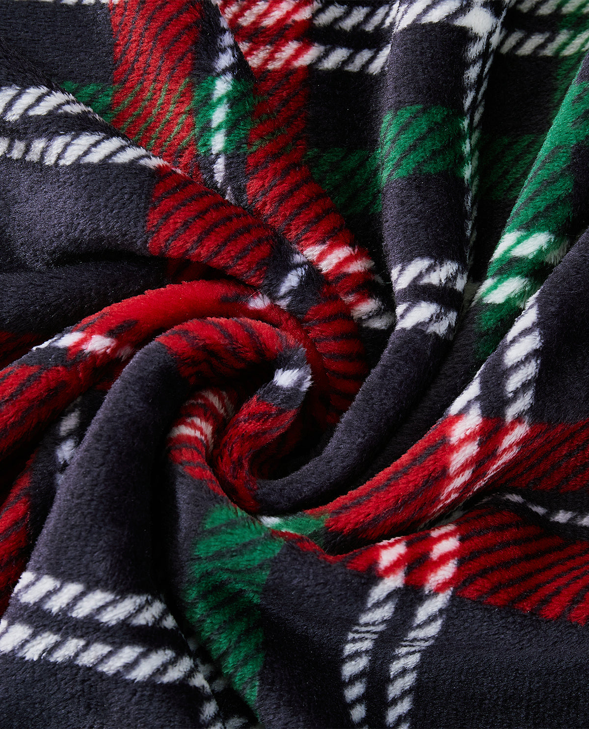 A close-up of a plush fleece blanket with a festive plaid pattern in red, green, white, and black, arranged in a spiral drape.