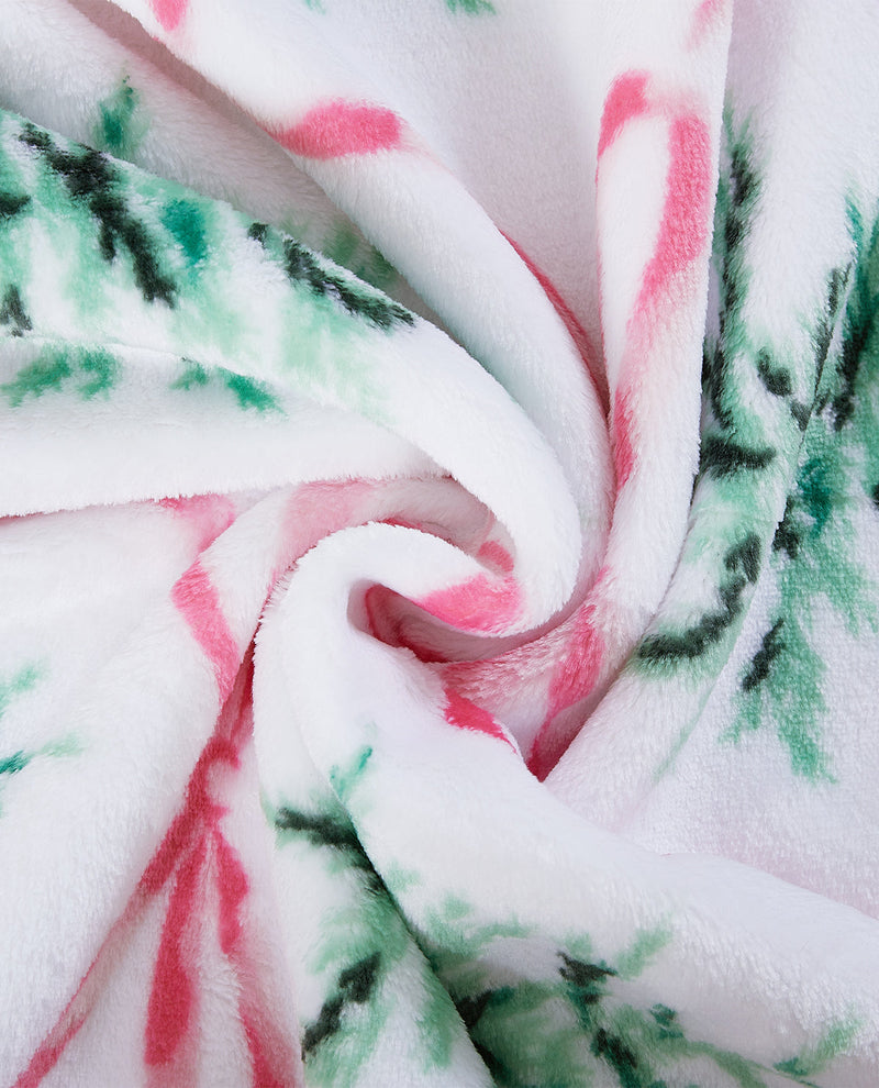 A close-up of a plush white fabric with a festive holiday pattern of green pine branches and pink accents, arranged in a spiral drape.
