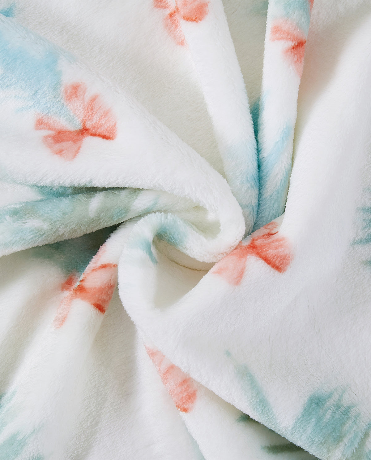 A close-up of a plush white fabric with soft pastel blue and coral pink tie-dye style watercolor patterns, arranged in a swirl.