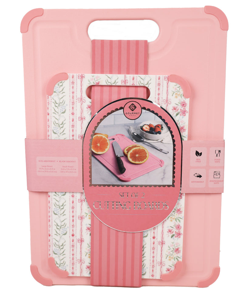 Pink cutting board set in its retail packaging, featuring a solid pink outer shell with corner bumpers and a handle, a floral patterned insert, and a central circular label showing the brand 'Gourmet Gadgets'.