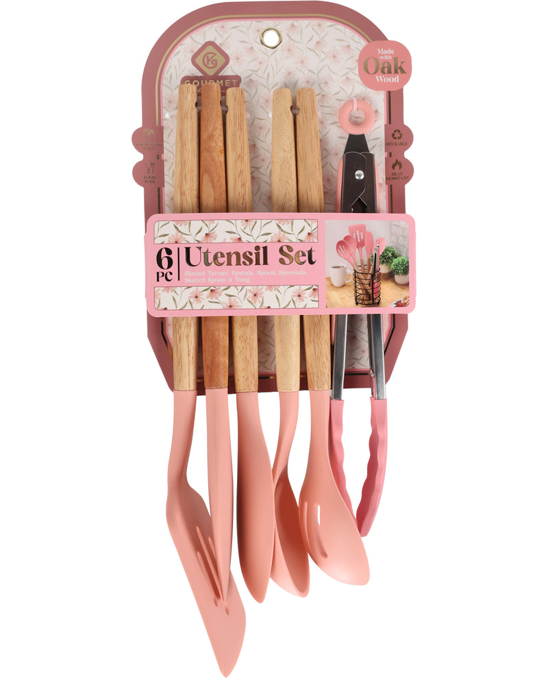 A 6-piece kitchen utensil set in a pink storage container, featuring pastel pink silicone spatulas, wooden-handled tools, and metal tongs, with a decorative pink label around the set.
